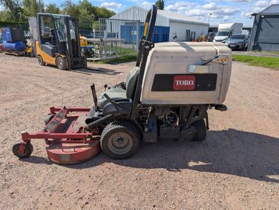 a tractor with a mower attached to it parked in the dirt