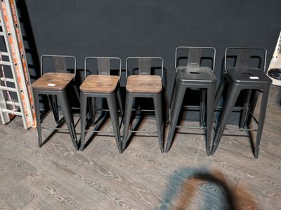 several stools are lined up against a black wall in a room