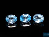 three blue topazte gems sit on a black surface