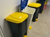 four trash cans lined up in a row next to each other