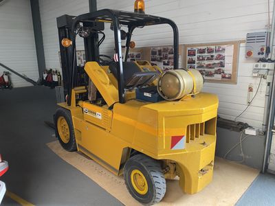 un chariot élévateur jaune avec un fût à l'arrière