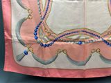 a pink scarf with blue beads and pearls on it