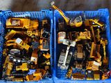 deux caisses remplies de petits engins de chantier en plastique posées par terre