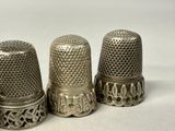 three silver thimbles sitting on top of a white surface