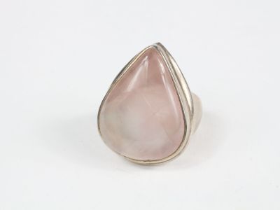 gros plan d'une bague en pierre rose sur une surface blanche
