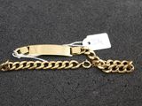 a close up of a gold chain bracelet with a tag on it