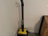 un aspirateur dans un coin de la pièce, à côté d'une commode