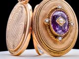 a gold locke with a purple stone inside of it
