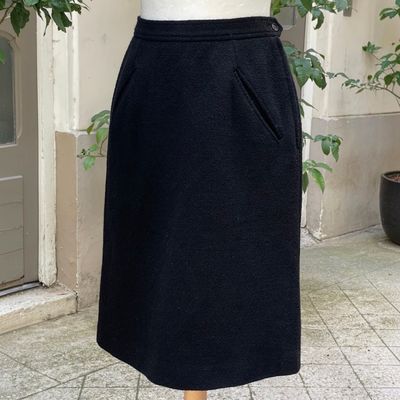 une jupe noire sur un mannequin posé sur un socle en bois