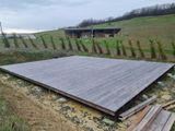 une grande terrasse en bois au milieu d'un champ
