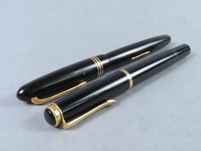 pair of black and gold fountain pens sitting on top of a table