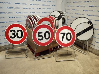 many signs that are sitting on the ground in front of a wall