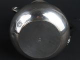 a silver tea pot sitting on a black surface