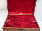 an open wooden box with red velvet linings on a white surface