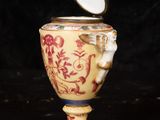 an antique vase with a lid on a black background