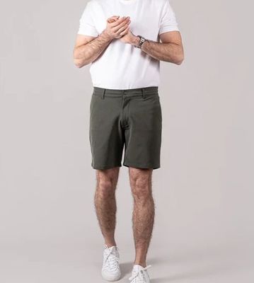 un homme en chemise blanche et short kaki posant pour une photo