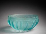 un saladier en verre bleu-vert posé sur une surface blanche