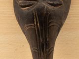 une image d'un masque en bois accroché au mur