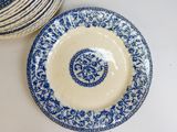a blue and white plate on the table next to a stack of plates