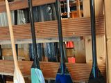 Plusieurs pagaies sont rangées sur un support dans un garage