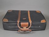 a black suitcase with a brown handle on a gray surface