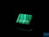 a close up of a green stone on a black surface