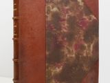 un gros plan d'un livre à la couverture marron posé sur une surface blanche