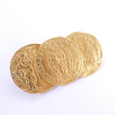 trois pièces d'or superposées sur une surface blanche
