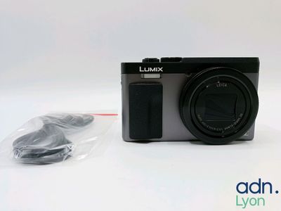 a black camera sitting next to a charger on a white table