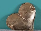 gold heart shaped broocht with a bow on top of it