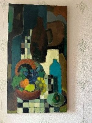 un tableau accroché au mur d'une pièce, représentant un vase rempli de fruits et une bouteille