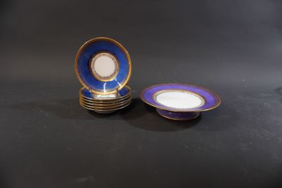 two blue and white plates with gold rims sitting on a black surface
