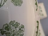 a close up of a green and white vase with flowers on it