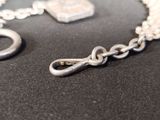 a silver chain with a clasp on a black surface