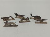 six figurines d'animaux en bronze posées sur des socles en bois, sur un fond blanc