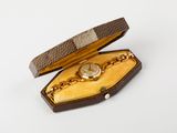 a small box with a watch in it on a white surface