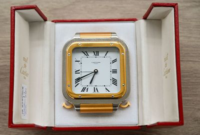 a gold and silver clock in a box on a table
