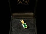 a close up of a gold and green ring in a black box