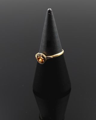 un gros plan d'une bague en or posée sur un cône noir