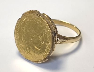 l'image d'une bague en or sur laquelle se trouve une pièce de monnaie