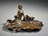 figurine en bronze représentant une femme assise sur une feuille, accompagnée d'un chien