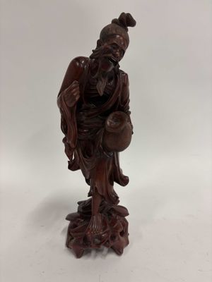 une vieille statue en bois représentant un homme assis sur un rocher