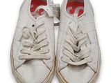 une paire de baskets blanches à semelles rouges sur un fond blanc