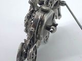 a silver brooch of a motorcycle with a man on it