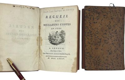 an old book with a pen sitting on top of it next to an open book