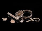 some silver jewelry is laying on a black surface with a black background
