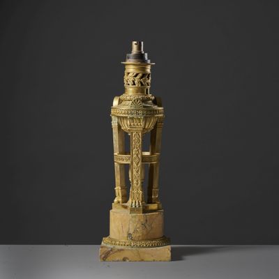 une statue en or représentant un homme sur un socle, surmontée d'un oiseau