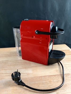 a small red coffee machine on a wooden table