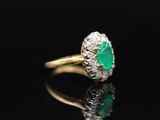 an emerald and diamond ring on a black surface