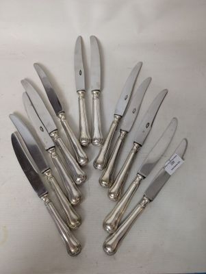 six silver plated knives are arranged in a circle on a white surface